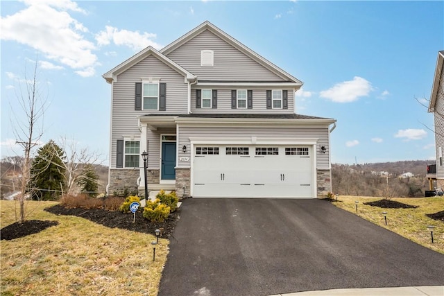 view of front of house with driveway, stone siding, an attached garage, and a front lawn