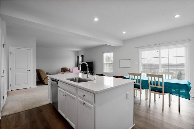 kitchen with dishwasher, open floor plan, a sink, a kitchen island with sink, and beam ceiling