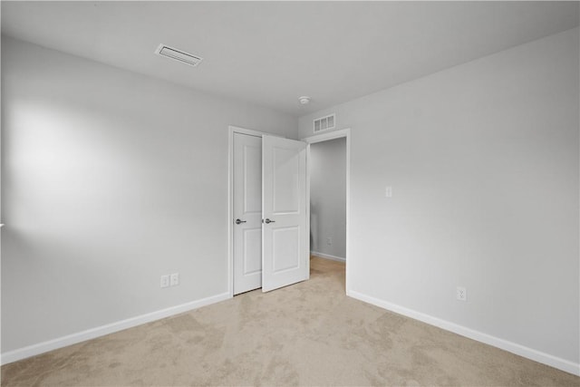 unfurnished bedroom with baseboards, visible vents, and light colored carpet