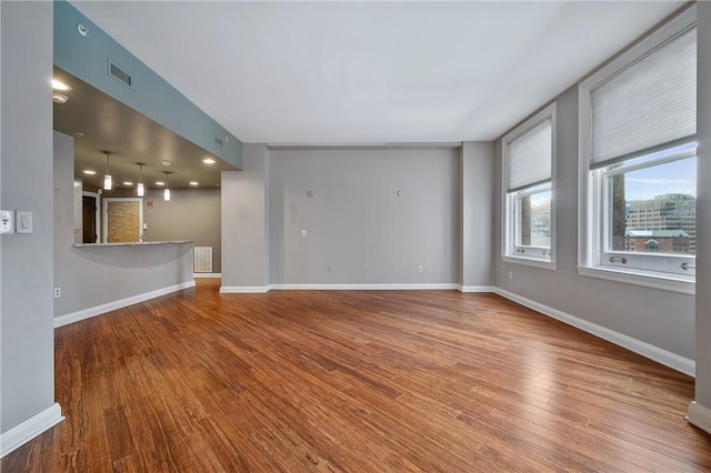 unfurnished room with wood finished floors, visible vents, and baseboards