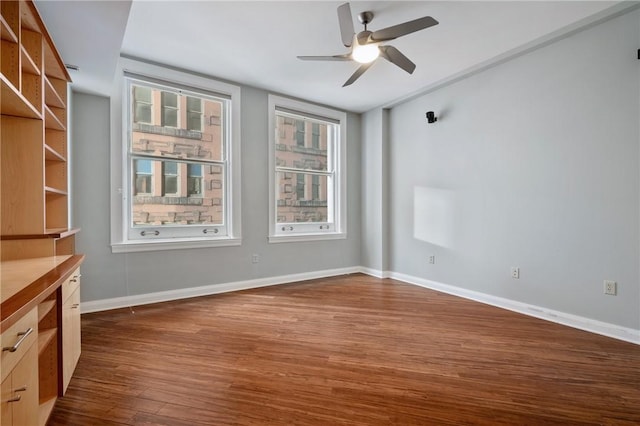 spare room with ceiling fan, baseboards, and dark wood-style flooring