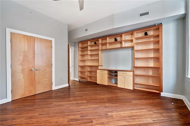 unfurnished living room featuring dark wood-style flooring, visible vents, and baseboards