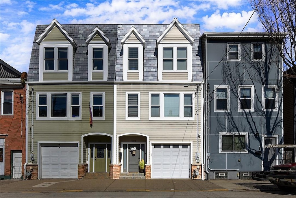 view of property with an attached garage and mansard roof