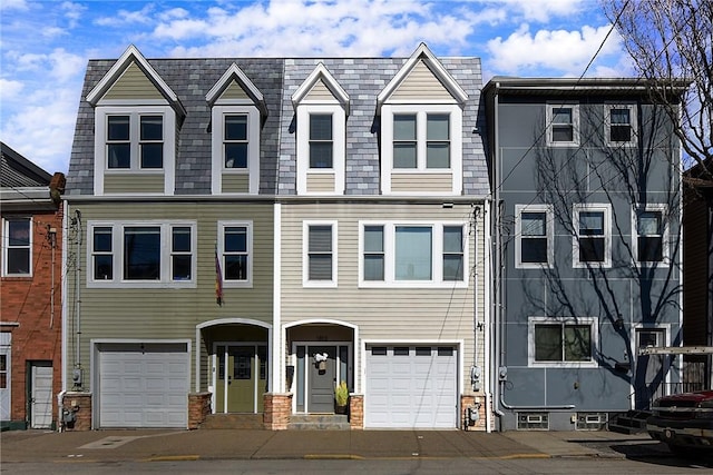 view of property with an attached garage and mansard roof