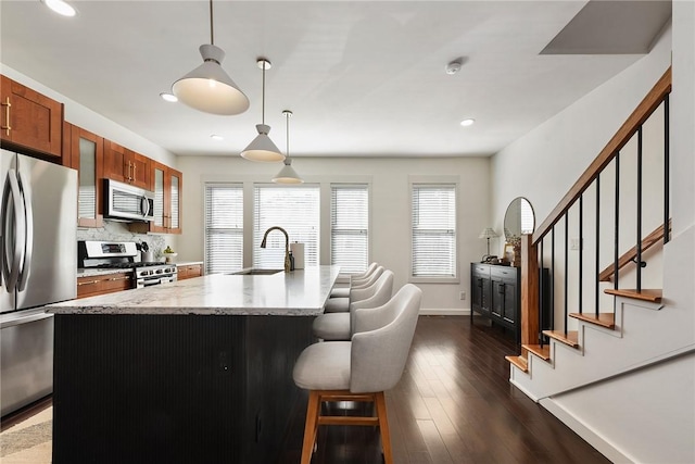 kitchen with dark wood finished floors, glass insert cabinets, a sink, stainless steel appliances, and a wealth of natural light