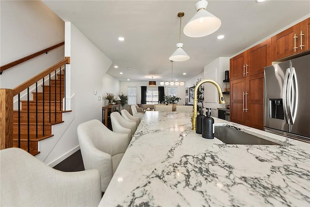 kitchen with open floor plan, light stone countertops, stainless steel refrigerator with ice dispenser, pendant lighting, and recessed lighting