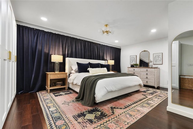 bedroom featuring arched walkways, baseboards, recessed lighting, and wood finished floors