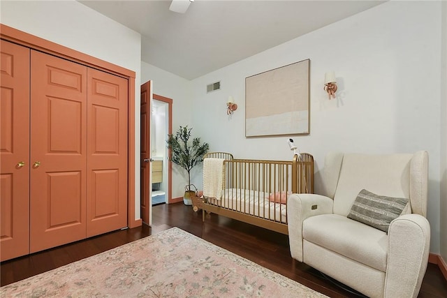 bedroom with dark wood-style floors, a closet, visible vents, and a ceiling fan