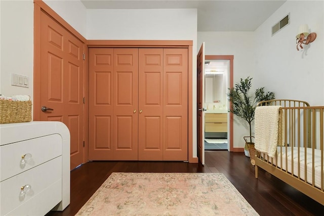 bedroom featuring ensuite bath, a closet, dark wood finished floors, and visible vents