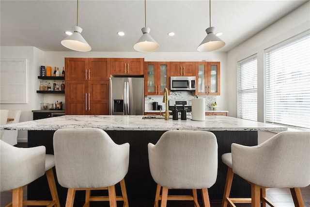 kitchen with appliances with stainless steel finishes, pendant lighting, brown cabinetry, and decorative backsplash