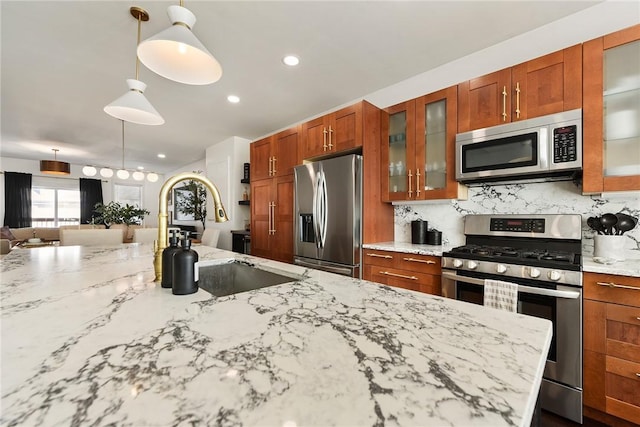 kitchen with appliances with stainless steel finishes, backsplash, a sink, and pendant lighting