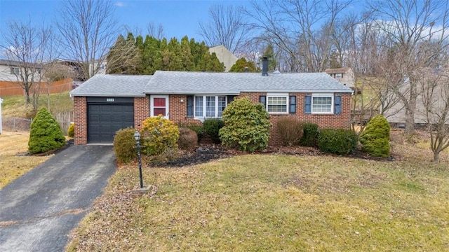 ranch-style home with a front yard, roof with shingles, an attached garage, aphalt driveway, and brick siding