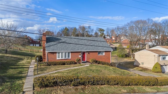 view of front of house with roof with shingles, a front lawn, a chimney, and brick siding