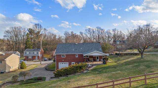 rear view of property featuring a garage, brick siding, fence, a yard, and driveway