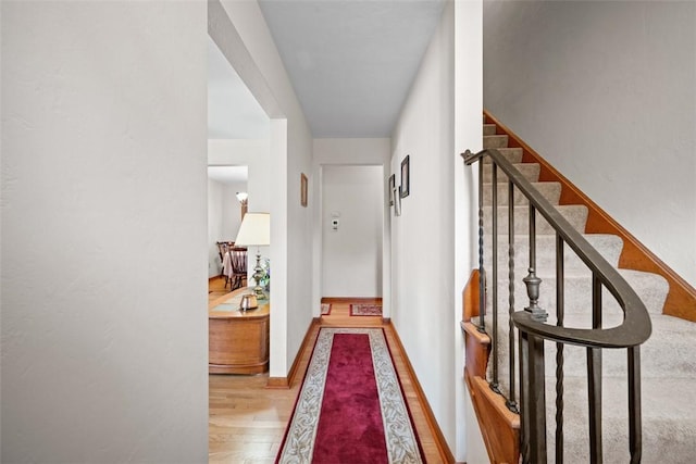 corridor featuring stairway, baseboards, and wood finished floors