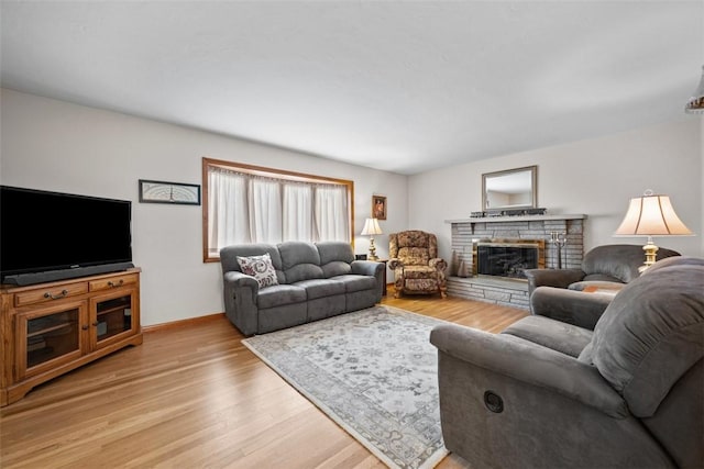 living area with a fireplace, light wood-style flooring, and baseboards