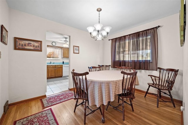 dining area with baseboards, light wood finished floors, and ceiling fan with notable chandelier