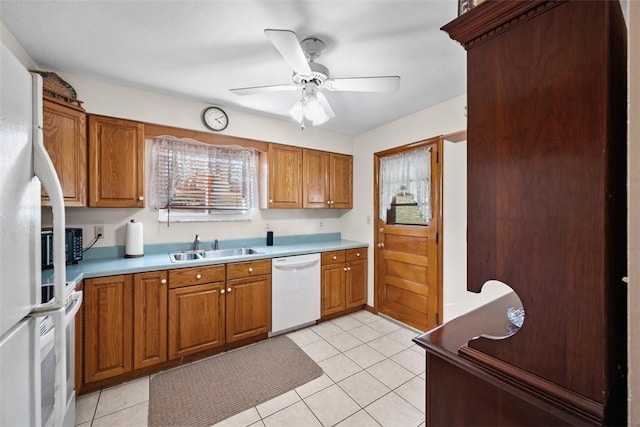 kitchen featuring light tile patterned floors, white appliances, a sink, and brown cabinets