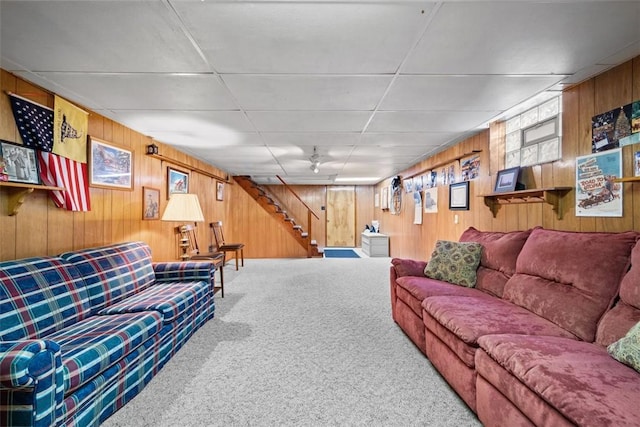 carpeted living area featuring stairs and wood walls