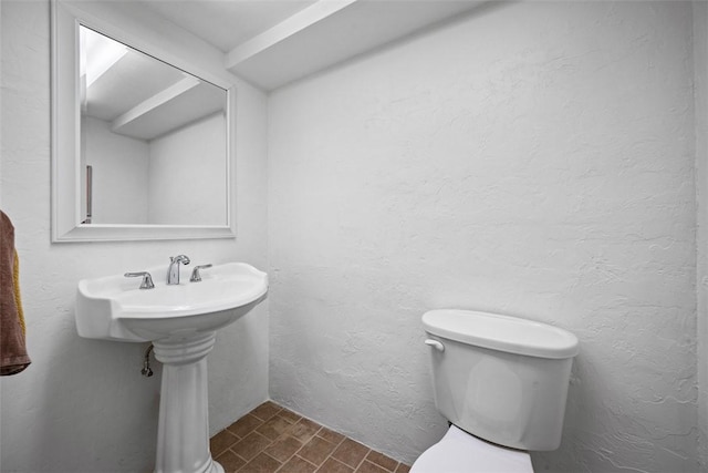 half bath with a textured wall and toilet