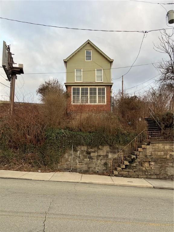 view of side of home with stairs and brick siding