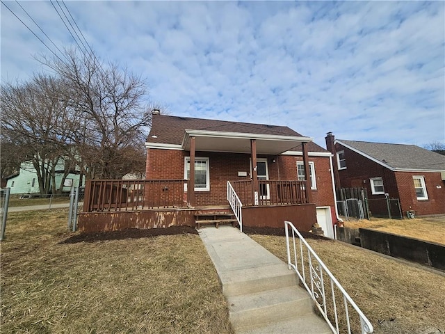 bungalow-style house featuring covered porch, brick siding, a front yard, and fence