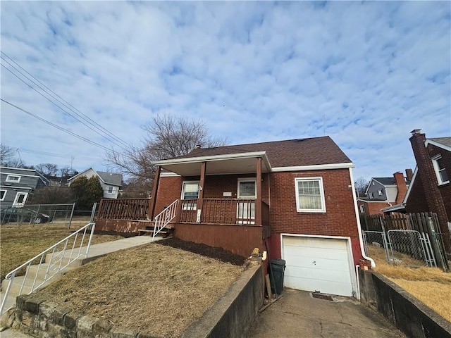 bungalow-style home with a garage, brick siding, driveway, and fence