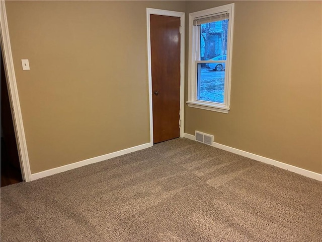 unfurnished bedroom featuring dark colored carpet, visible vents, and baseboards