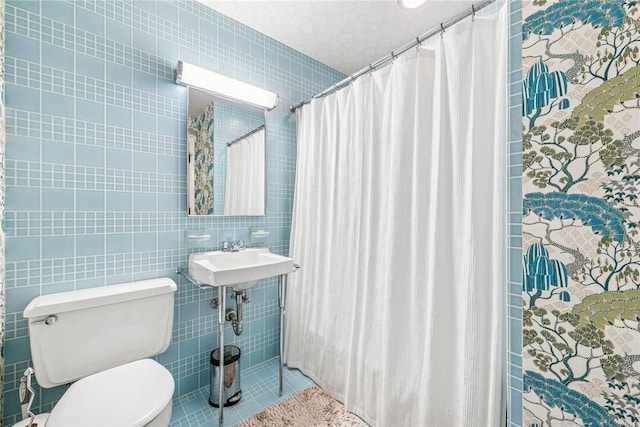 bathroom featuring toilet, a sink, tile walls, and a shower with curtain