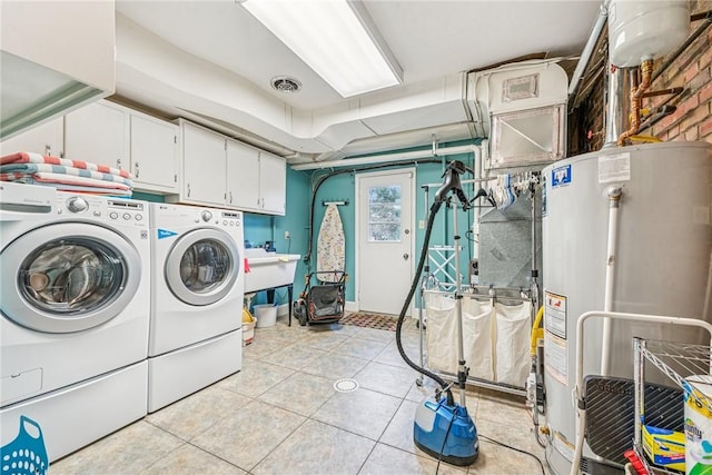 laundry area featuring washing machine and clothes dryer, water heater, cabinet space, visible vents, and light tile patterned flooring