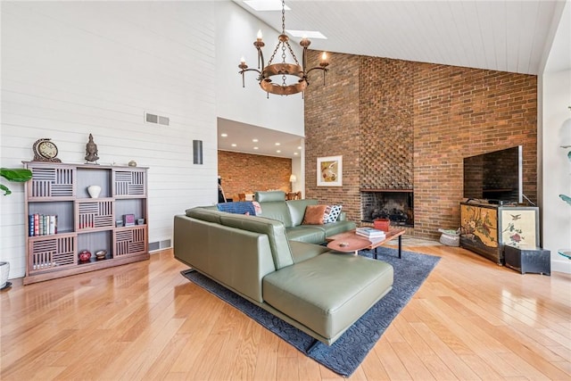 living area with wood-type flooring, a fireplace, visible vents, and an inviting chandelier