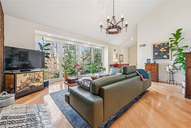 living area with high vaulted ceiling, wood-type flooring, visible vents, and a notable chandelier