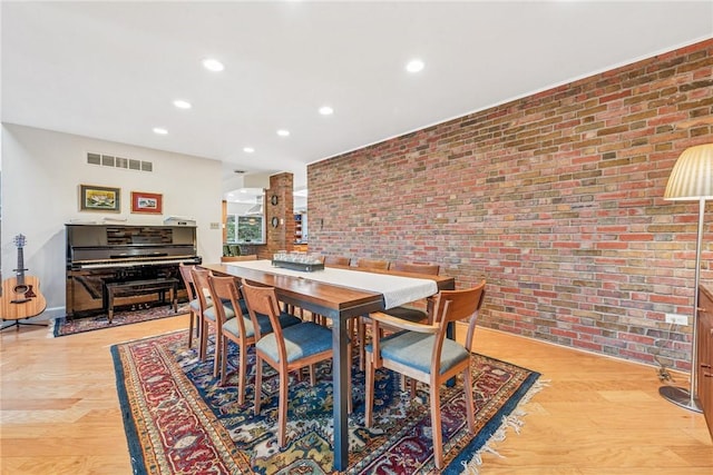 dining room featuring brick wall, light wood-type flooring, visible vents, and recessed lighting