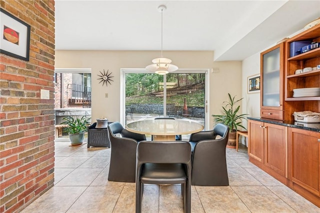 dining space with light tile patterned floors, brick wall, and a healthy amount of sunlight