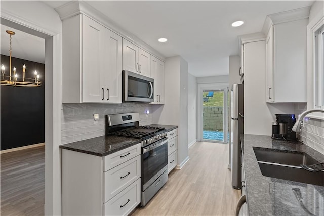 kitchen with light wood finished floors, white cabinetry, appliances with stainless steel finishes, and a sink