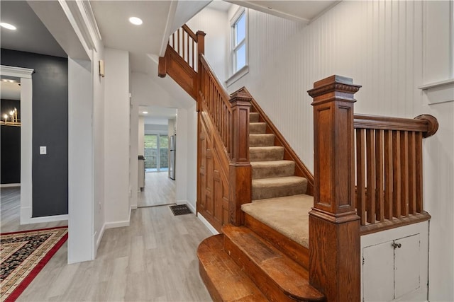 staircase featuring baseboards, wood finished floors, and recessed lighting