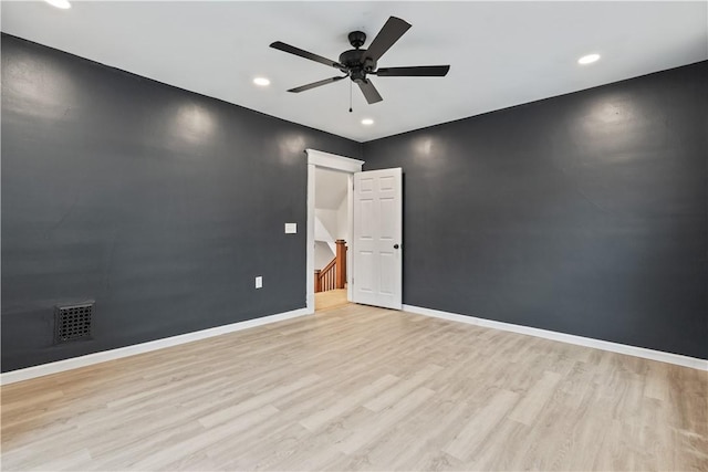 spare room featuring an accent wall, light wood-style flooring, baseboards, and a ceiling fan