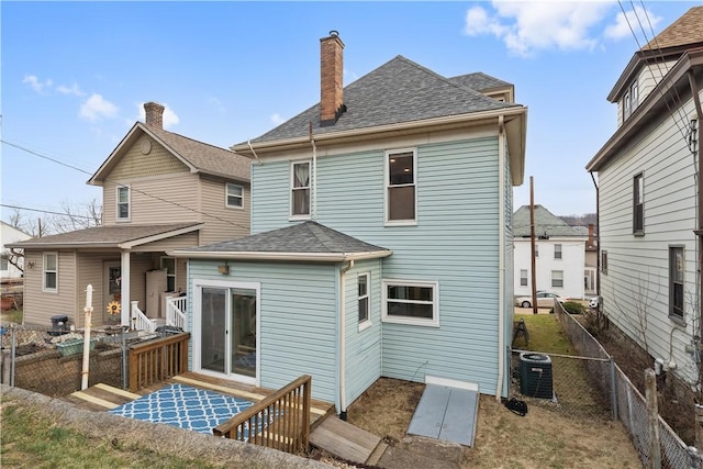 rear view of house with central AC, roof with shingles, a chimney, and fence