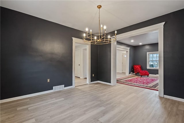 unfurnished dining area with baseboards, visible vents, light wood finished floors, and an inviting chandelier