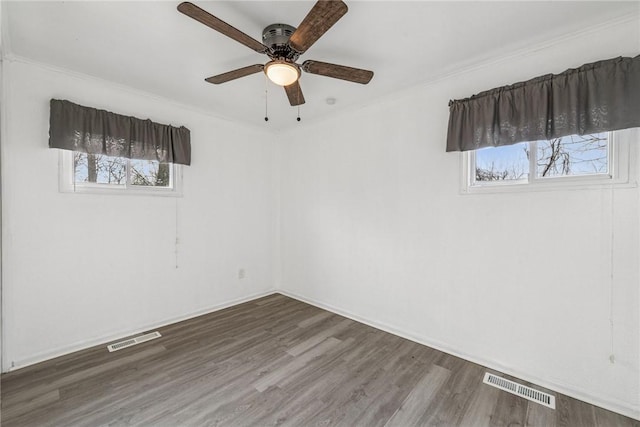 spare room with a ceiling fan, visible vents, baseboards, and wood finished floors