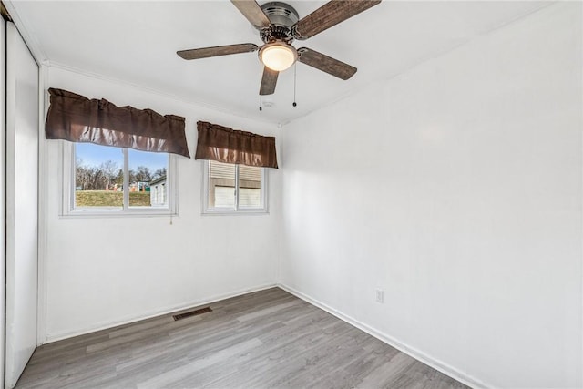 spare room with baseboards, ceiling fan, visible vents, and wood finished floors