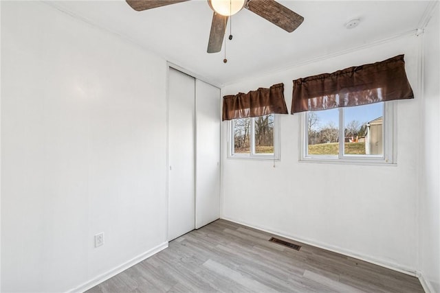 unfurnished room with baseboards, visible vents, ceiling fan, and wood finished floors