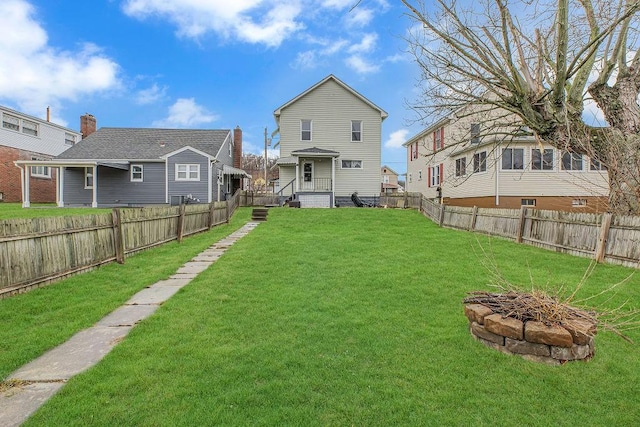 rear view of house featuring a fire pit, a yard, and a fenced backyard