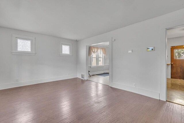 unfurnished room featuring hardwood / wood-style floors, visible vents, and baseboards