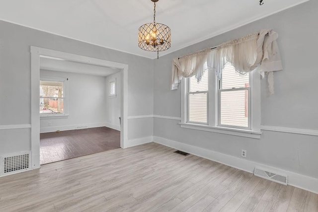 unfurnished dining area with a notable chandelier, visible vents, and wood finished floors