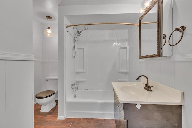 bathroom with a wainscoted wall, bathing tub / shower combination, toilet, vanity, and wood finished floors