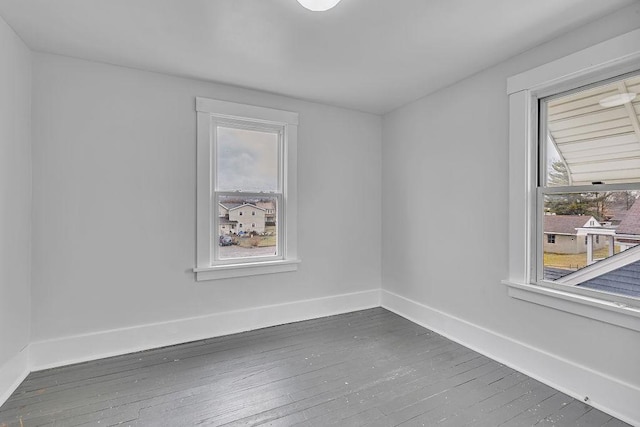 unfurnished room with baseboards and dark wood finished floors