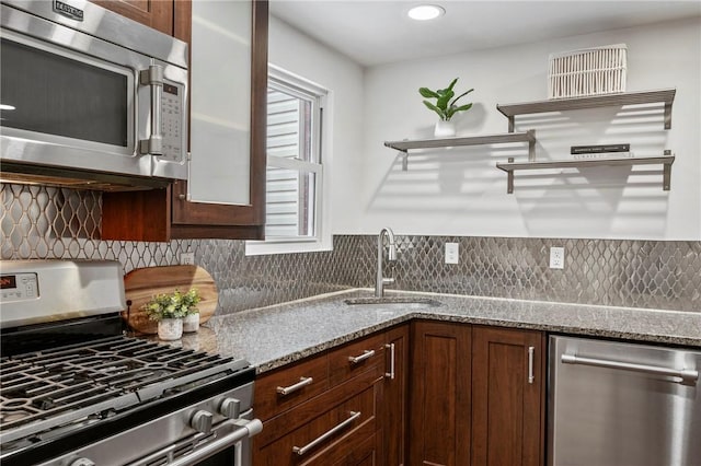 kitchen featuring appliances with stainless steel finishes, a sink, light stone counters, and decorative backsplash