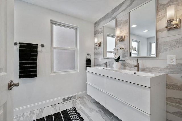 bathroom featuring marble finish floor, double vanity, a sink, and visible vents