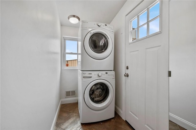 laundry area with laundry area, plenty of natural light, visible vents, and stacked washer / dryer